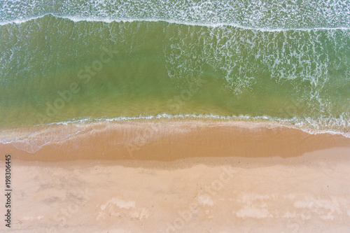 Aerial view of sandy beach and ocean with waves, overhead shot.