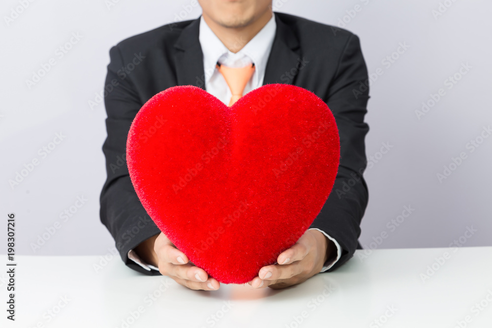 Businessman holds out the red heart, isolated background Businessman holds out the red heart, isolated background