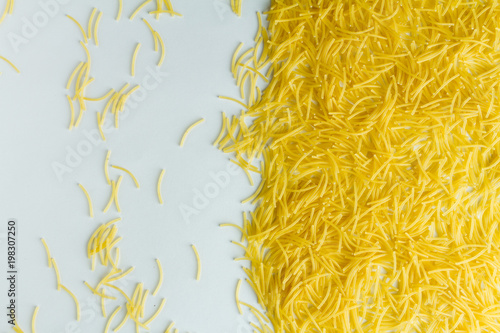 Macaroni evenly scattered on a white table.