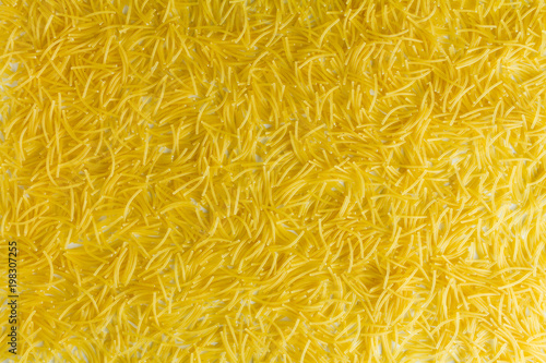 Macaroni evenly scattered on a white table.