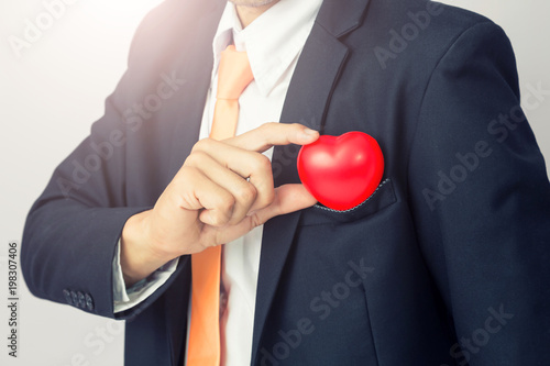 Businessman holds out the  red heart, isolated background © PRASERT