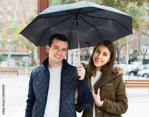 couple walking under umbrella at autumn day