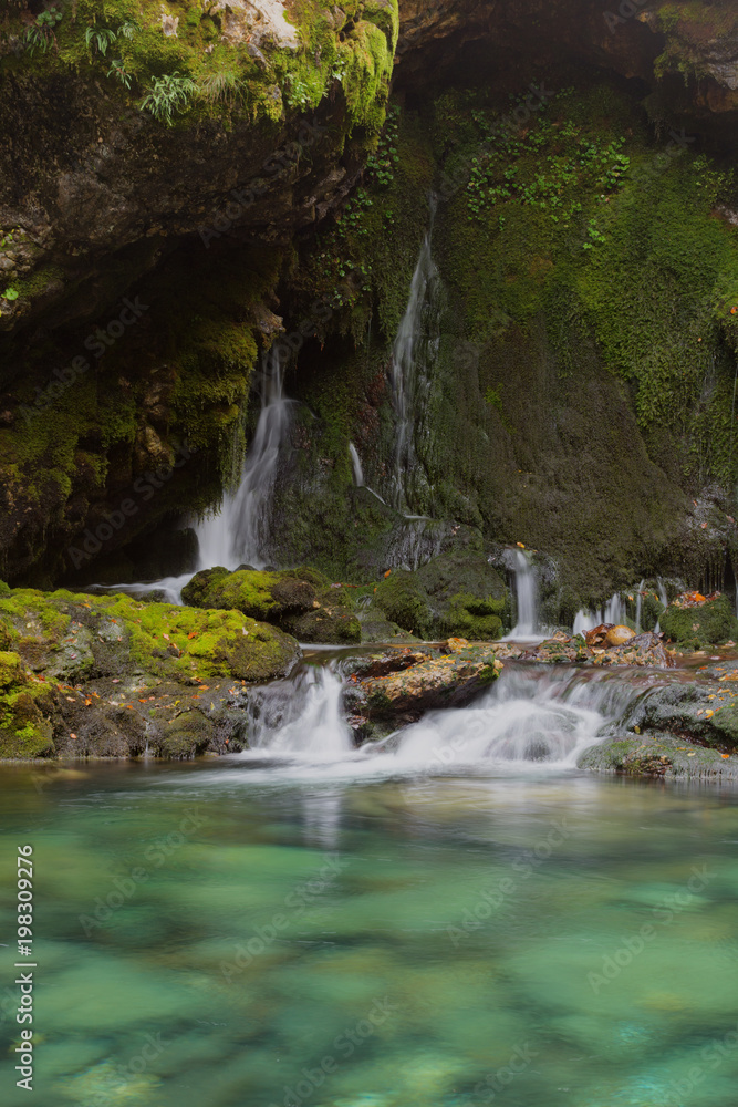 Smoll waterfall among rocks covered with green moss Smoll waterfall among rocks covered with green moss
