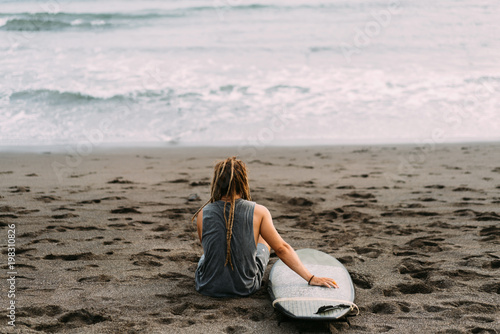 Surfer with dreadlocks with surfingboard near ocean photo