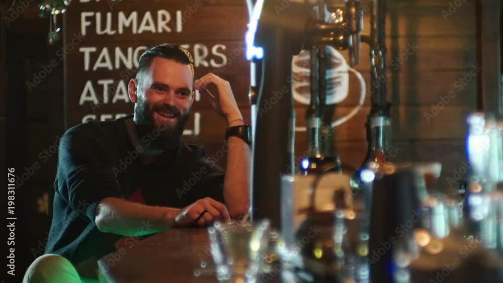 Bearded guy drinks a cocktail and communicates with the bartender at the bar counter in 4k resolution in slow motion Bearded guy drinks a cocktail and communicates with the bartender at the bar counter in 4k resolution in slow motion