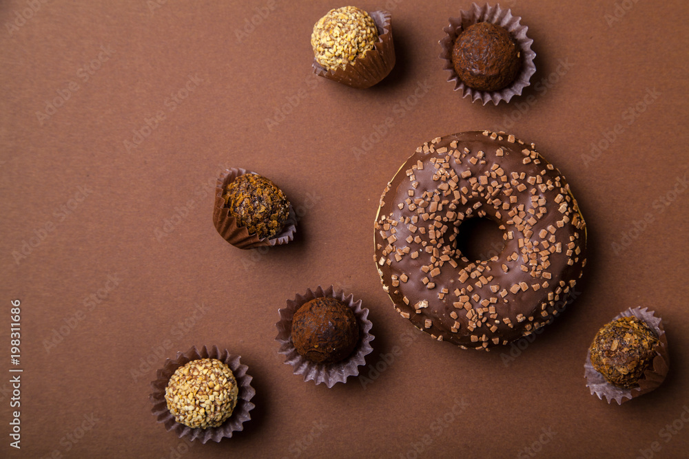 Chocolate donuts with chocolate truffles on brown background. Monochromatic concept. Chocolate donuts with chocolate truffles on brown background. Monochromatic concept.