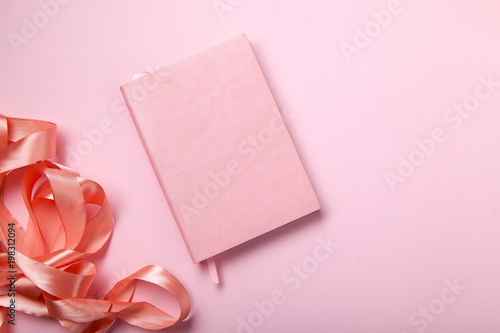 Pink notebook with shiny pink satin ribbon on pink background. Monochromatic concept. © Anastasiia Nurullina