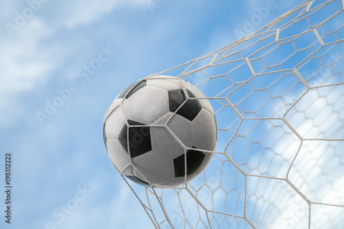 Soccer ball on goal with net and sky background