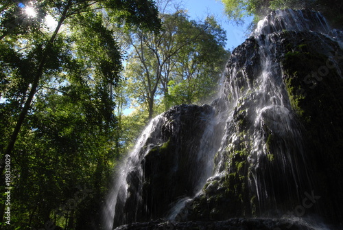 Rayos de sol atravesando el agua que cae de la cascada