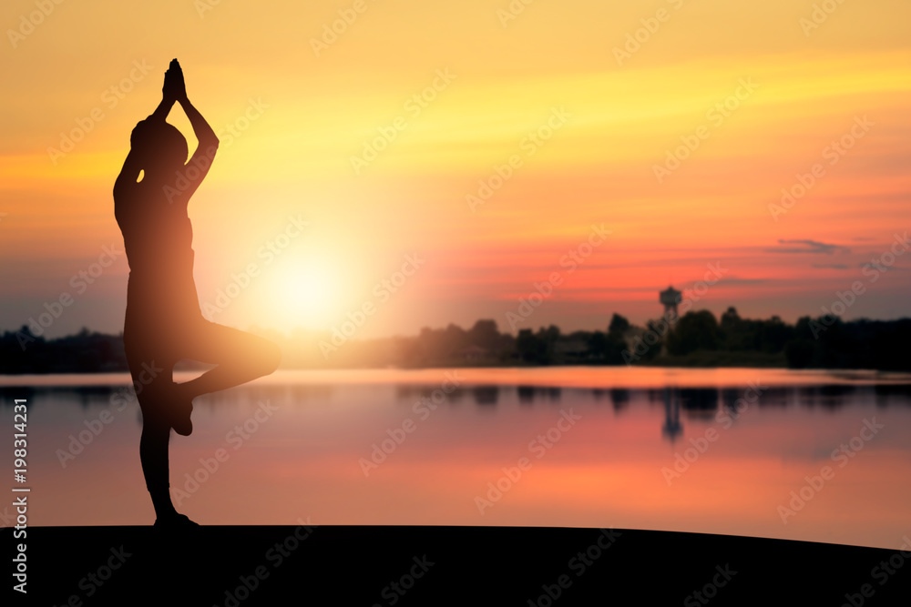 silhouettte of women doing yoga in park.