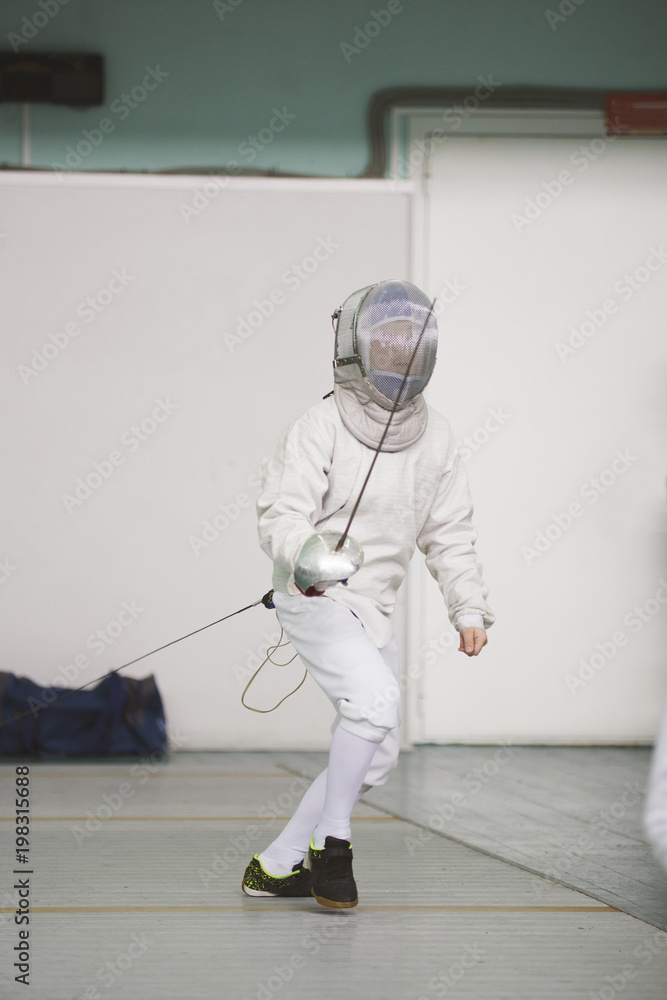 Boy teenager fencer in special costume at the fencing competition with rapier ready for fight