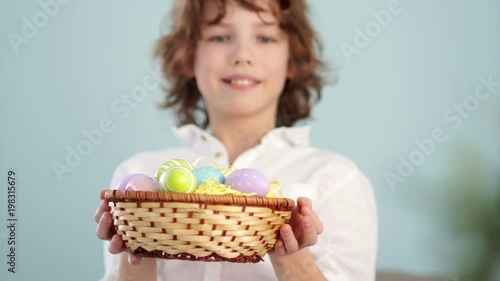 Clouse up ap portrait of a curly red-haired boy with a basket of Easter eggs in his hands. Happy easter photo