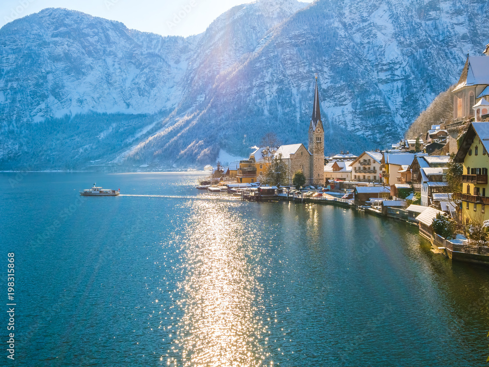 Classic postcard view of famous Hallstatt lakeside town in the Alps moutain  ship on a beautiful cold sunny day with blue sky and clouds in winter, Salzkammergut region, Austria