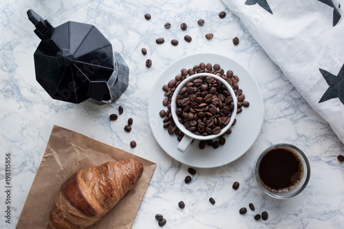 Flat Lay with coffee beans, espresso, croissant and coffee percolator on marble background