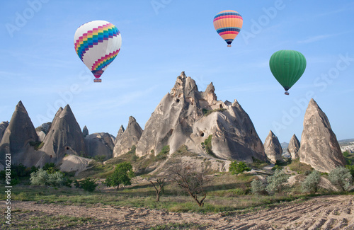 Colorful hot air balloons flying over unique geological formations in Cappadocia, Central Anatolia, Turkey