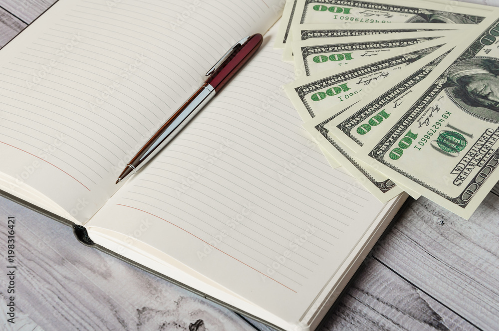 Notepad, pen and money on a light wooden background Notepad, pen and money on a light wooden background