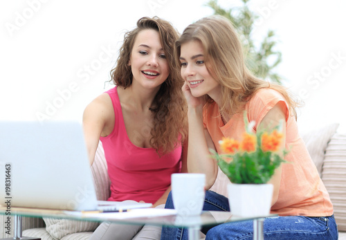 two young women discuss the video with laptop sitting at a coffee table
