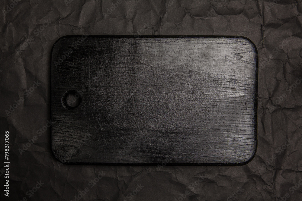 Black cutting board on black paper background. Top view. Black cutting board on black paper background. Top view.
