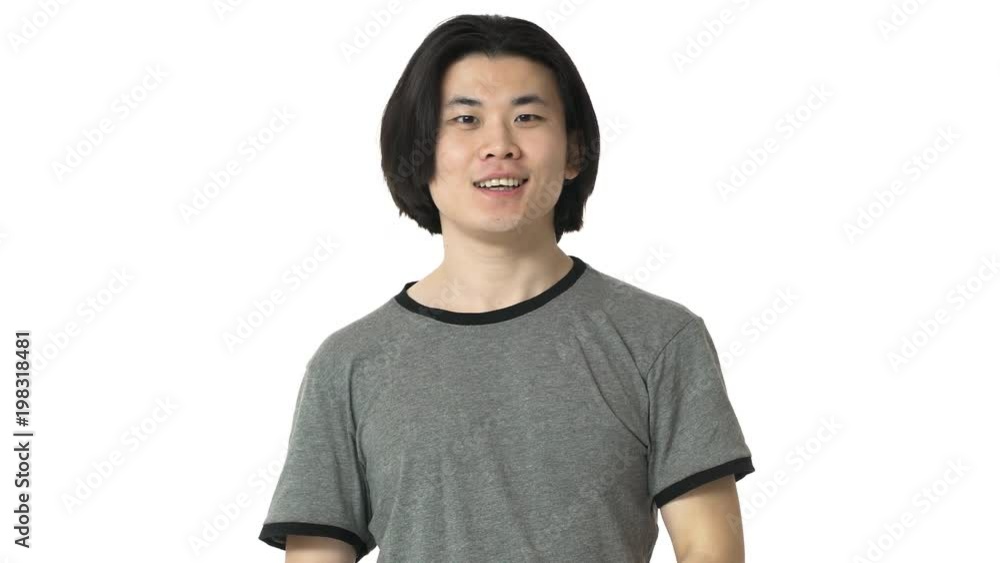 Portrait of friendly chinese man with clean skin in casual gray t-shirt grinning and greeting with waving hand on camera, over white background. Concept of emotions Portrait of friendly chinese man with clean skin in casual gray t-shirt grinning and greeting with waving hand on camera, over white background. Concept of emotions