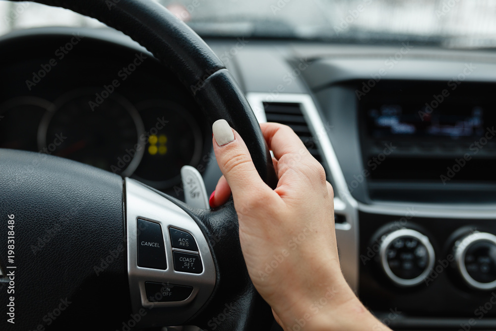 Close-up of woman's hand holding a steering wheel. Girl driver rides behind the wheel of a large car or SUV.