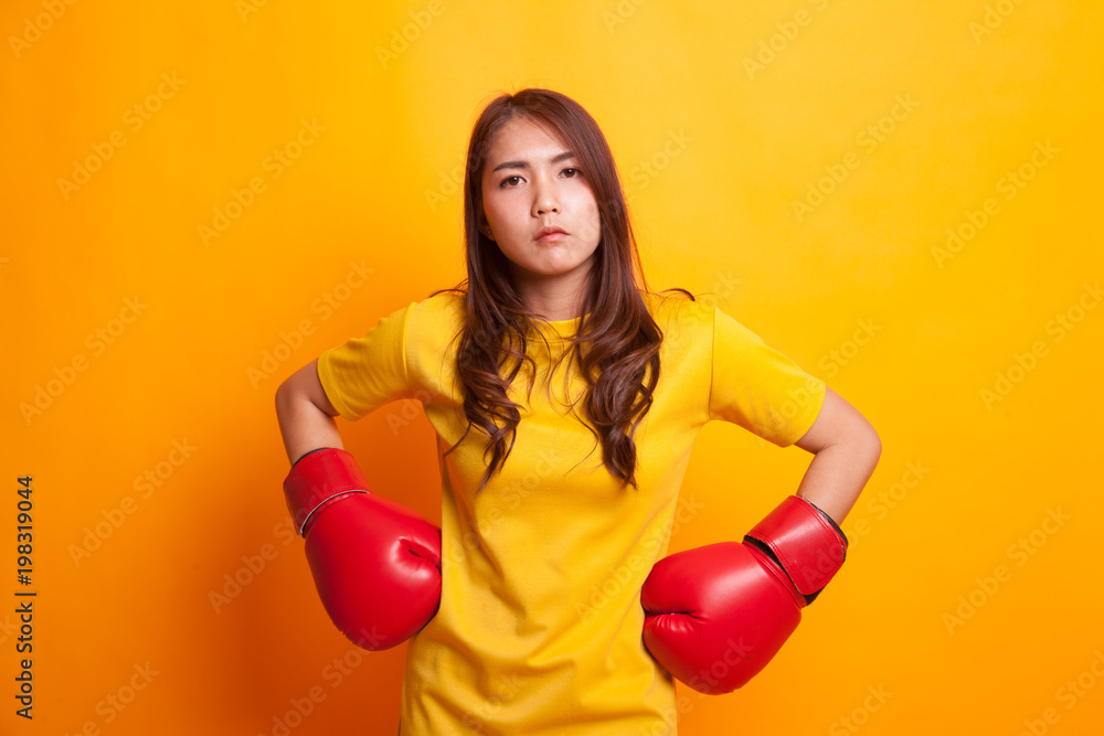 Young Asian woman with red boxing gloves in yellow dress