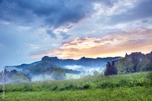 Mystical landscape with sunrise and morning fog in the mountains