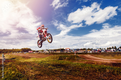 Fototapeta Naklejka Na Ścianę i Meble -  Racer on dirtbike motorcycle jumps and takes off over the track, in background opponent is catching up. Concept primacy, rivalry, competition, extreme
