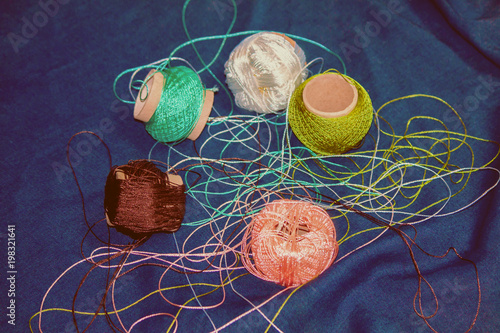 Threads for knitting on a blue background. Handmade concept. Crochet hooks and multi-colored yarn look bright.