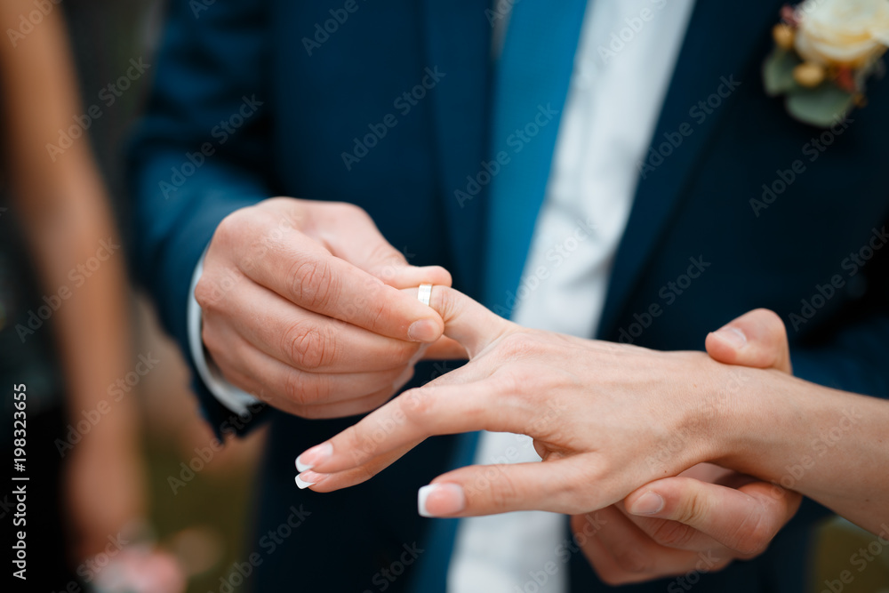 Wedding ceremony with bride and groom putting golden rings on each other fingers