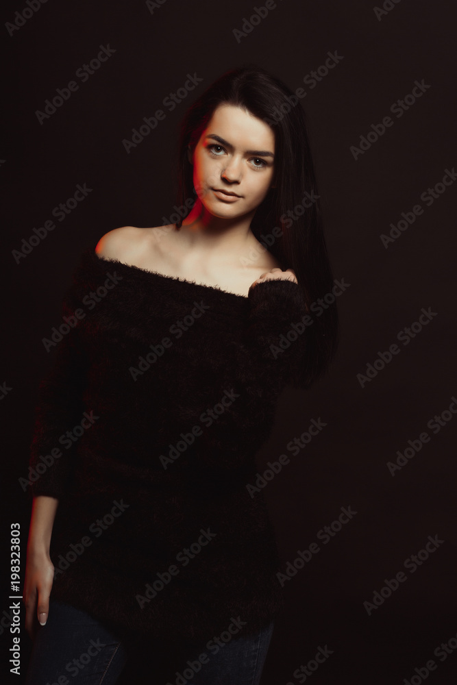 Model test with gorgeous brunette lady in knitted sweater posing over a black studio background Model test with gorgeous brunette lady in knitted sweater posing over a black studio background
