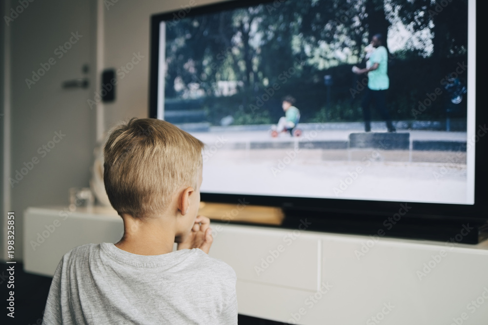 Rear view of boy watching smart TV in living room at home Rear view of boy watching smart TV in living room at home