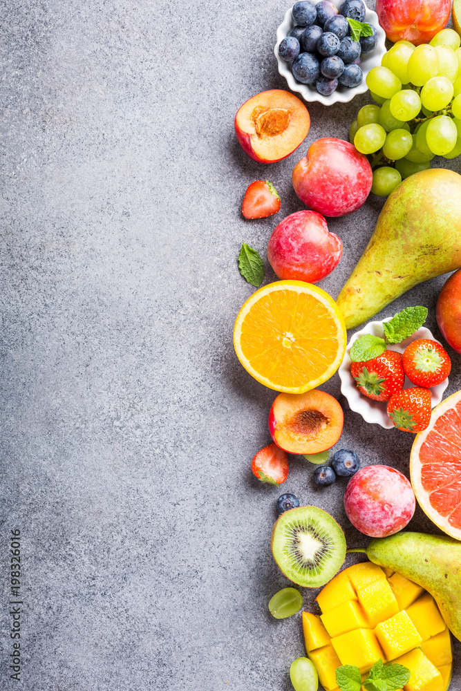 Fresh assorted fruits and berries on light gray background. Colorful clean and healthy eating. Detox food. Copy space. Top view. Fresh assorted fruits and berries on light gray background. Colorful clean and healthy eating. Detox food. Copy space. Top view.