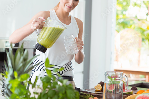 Happy woman pouring green cocktail photo