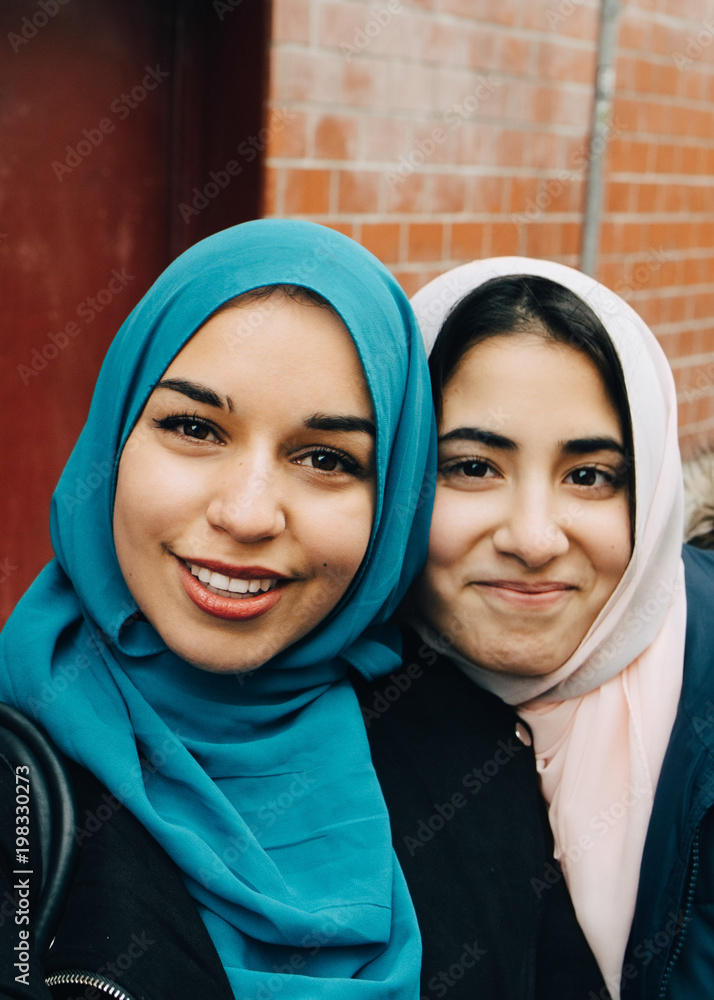 Portrait of smiling young woman taking with teenage friend against building in city Portrait of smiling young woman taking with teenage friend against building in city