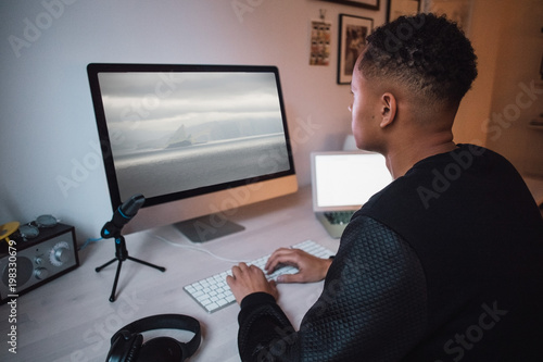 Young male freelance worker using computer at desk photo