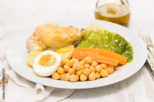 boiled cod fish with potato, carrot, cabbage , chick-pea and egg on white plate