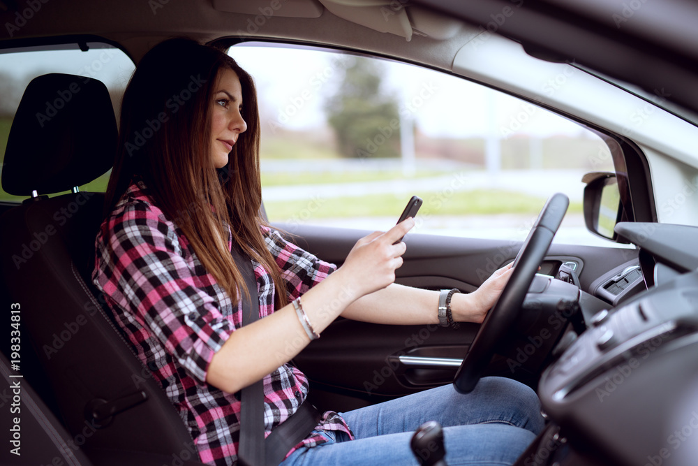 Young careless cute girl is texting and driving at same time. Young careless cute girl is texting and driving at same time.