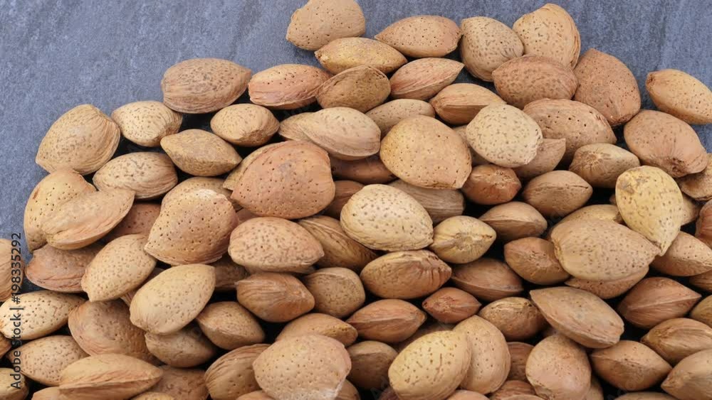 Almonds falling on grey stone background Almonds falling on grey stone background