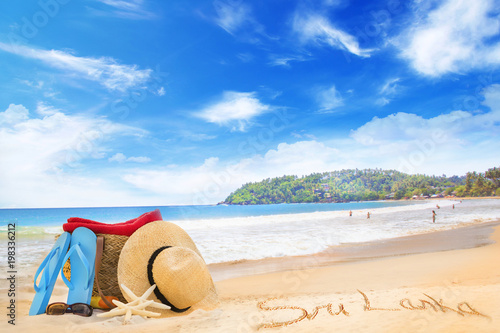 Fototapeta Naklejka Na Ścianę i Meble -  Straw hat, sunglasses, slippers and a bag on the golden sand of Sri Lanka's beach