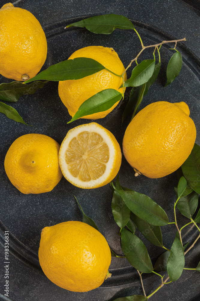 Fresh juicy fruit citrus lemon and slices on a dark wooden background with leaves with copy space flat lay top view