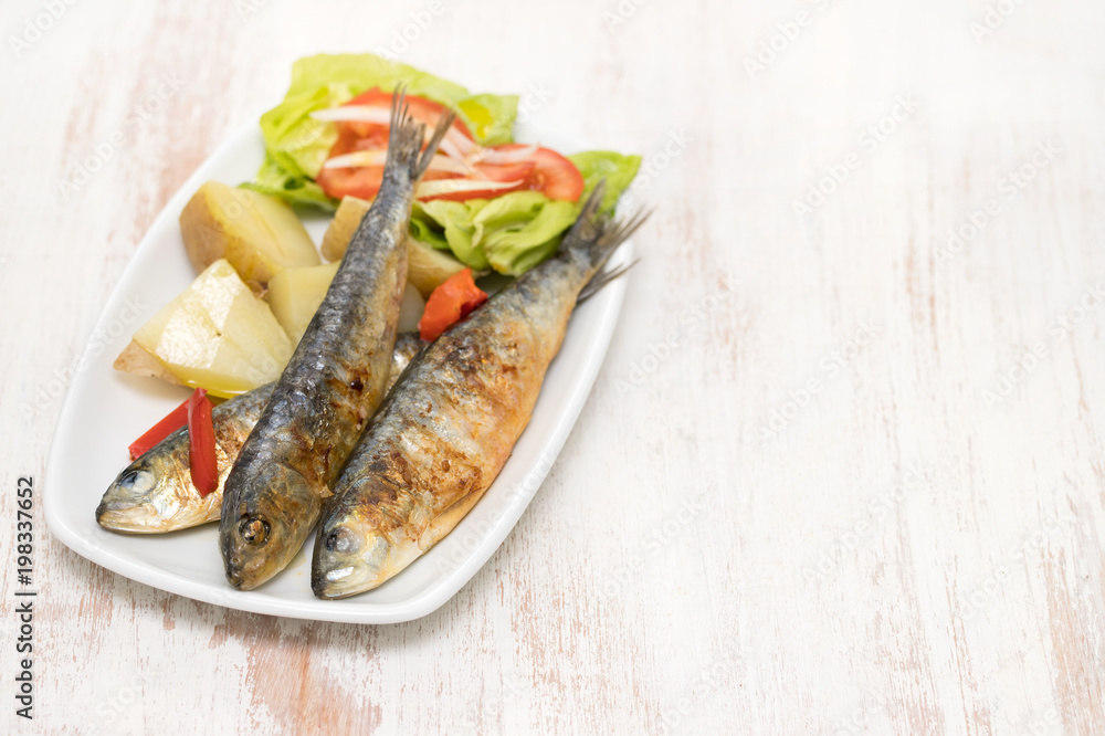 grilled sardines with boiled potato and salad on white plate grilled sardines with boiled potato and salad on white plate