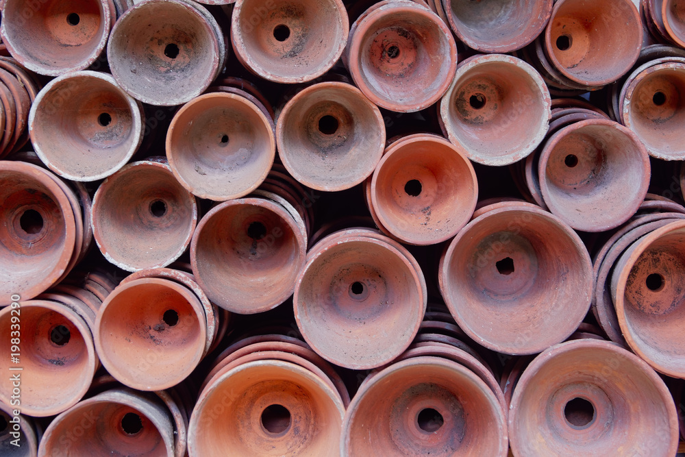 Fototapeta premium Rows of clay plant pots stacked neatly on their sides.