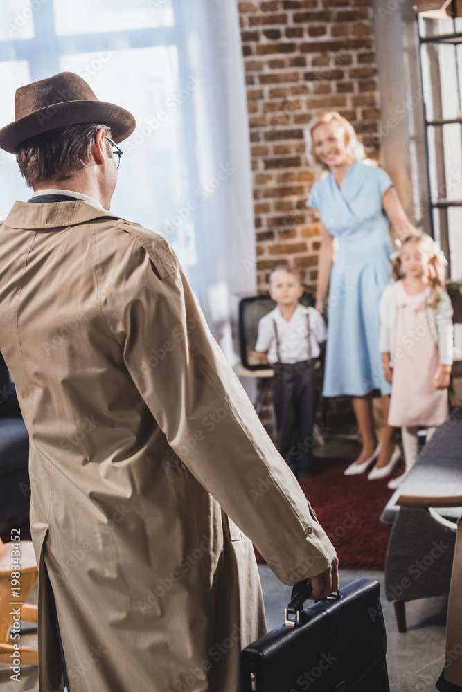 back view of father with briefcase coming home and looking at happy family, 1950s style back view of father with briefcase coming home and looking at happy family, 1950s style