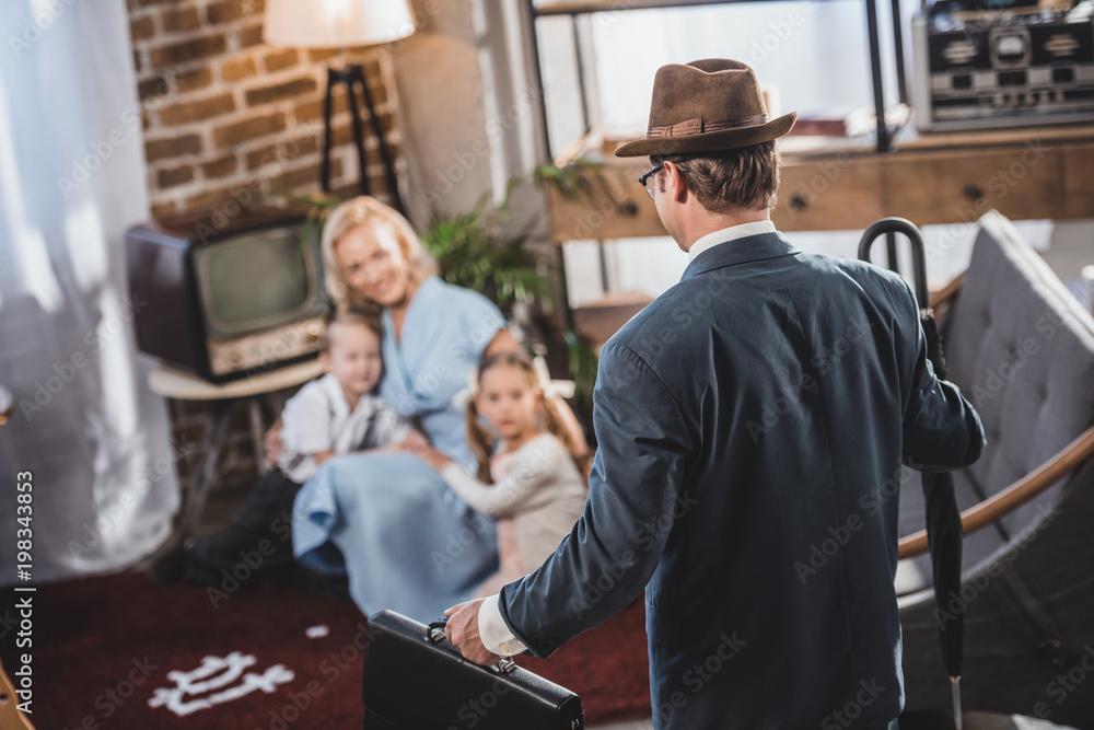 selective focus of mother with two kids playing together and looking at father coming home, 1950s style selective focus of mother with two kids playing together and looking at father coming home, 1950s style