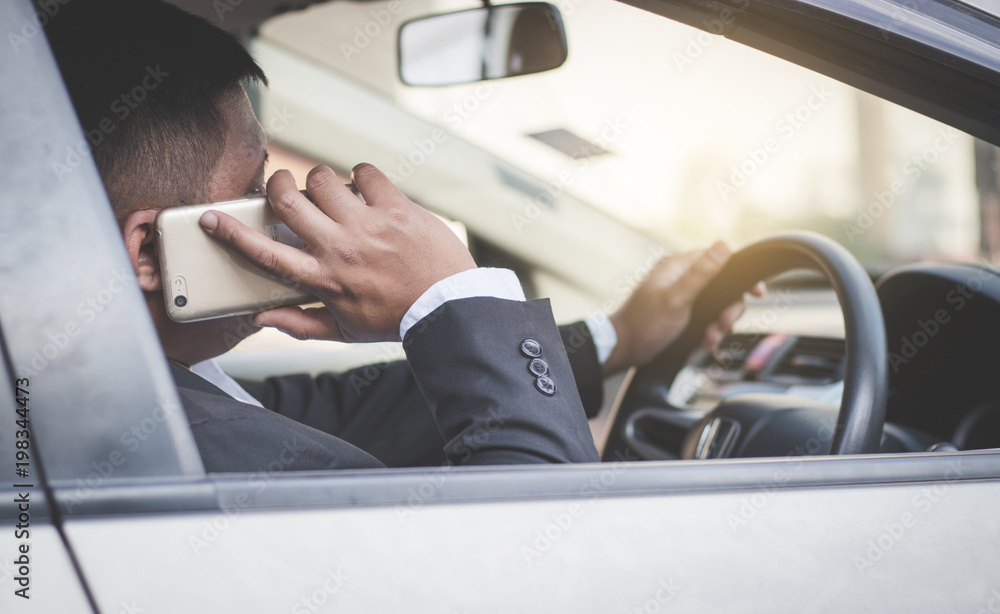 Businessman using smartphone in car.