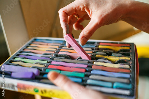 Wallpaper Mural Set of multicolored pastel crayons in open artist box in woman hands. Artist painting on easel Torontodigital.ca