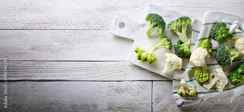 Cauliflower, romanesco broccoli and sicilian broccoli on white wood background