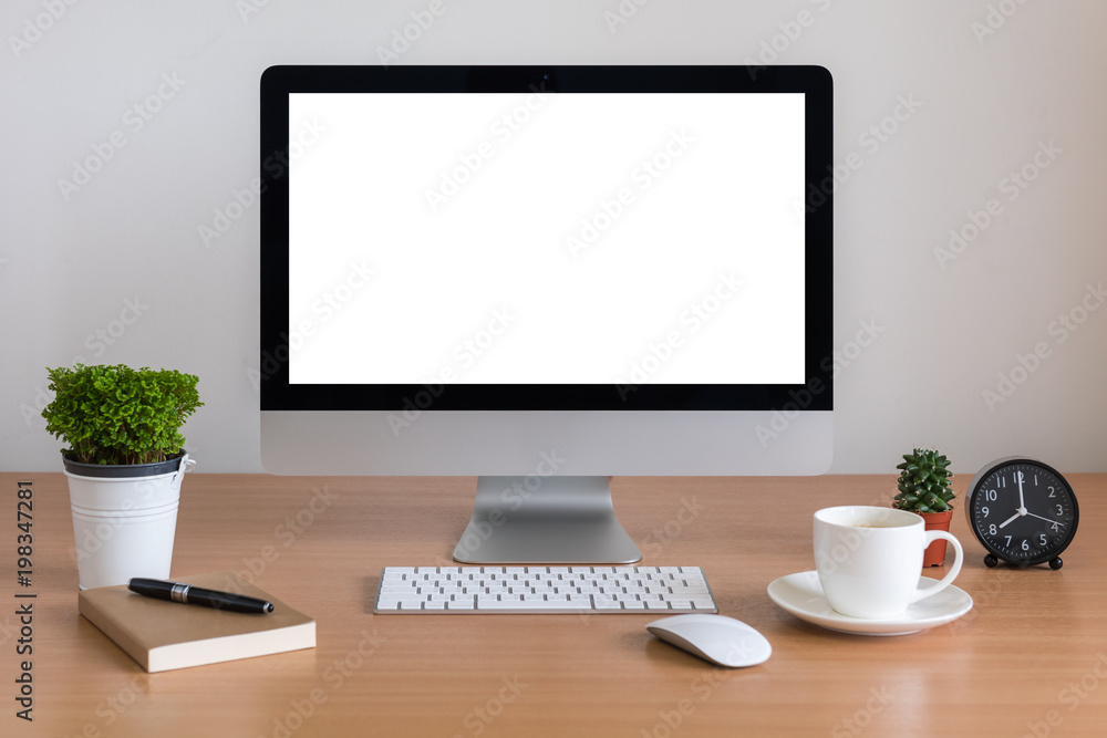 All in one computer, mouse, keyboard, clock, note book, pen and tree vase on wooden table All in one computer, mouse, keyboard, clock, note book, pen and tree vase on wooden table
