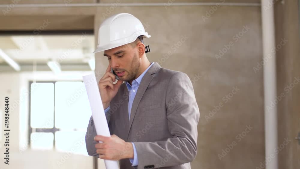 architecture, construction business and people concept - architect with blueprint and helmet calling on smartphone at office architecture, construction business and people concept - architect with blueprint and helmet calling on smartphone at office
