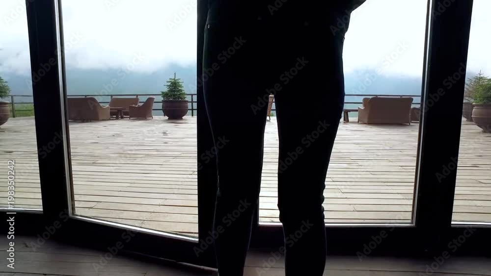 Beautiful woman walking out to the terrace of amazing hotel and looking at the Georgian mountains Beautiful woman walking out to the terrace of amazing hotel and looking at the Georgian mountains